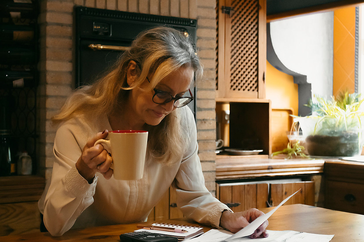 Woman drinking coffee while preparing house budget standing at home Gasverbrauch berechnen